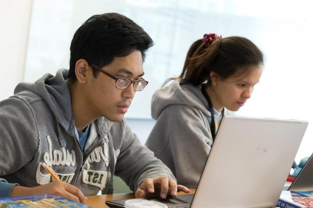 Two students work side by side on computers in a Temple classroom.